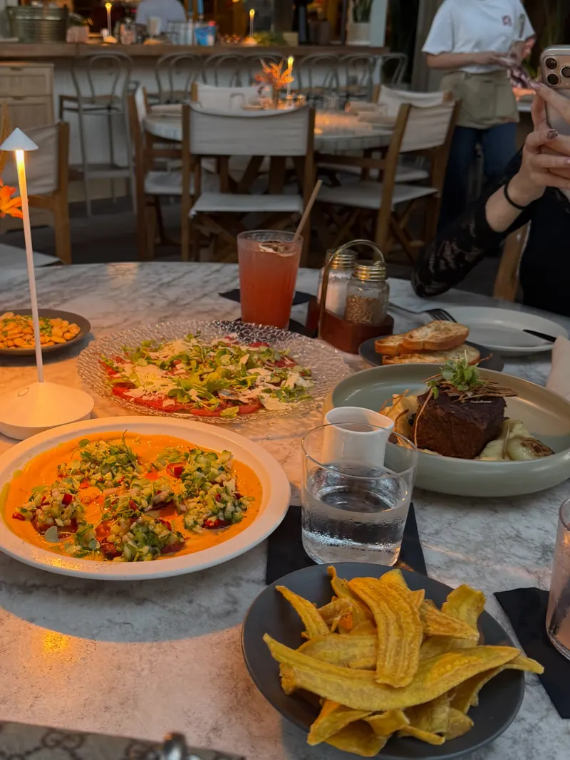 A dinner table with shared plates, plantain chips and a small lamp
