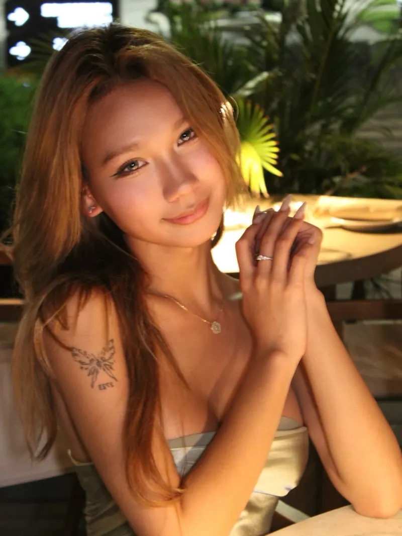 Golden-hour portrait at a dinner table, hands clasped, satin bandeau top